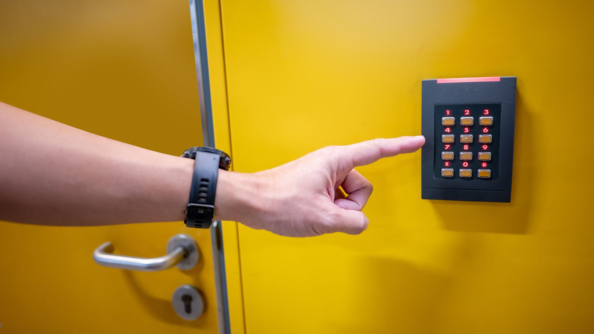 Male finger pressing password number on digital door lock